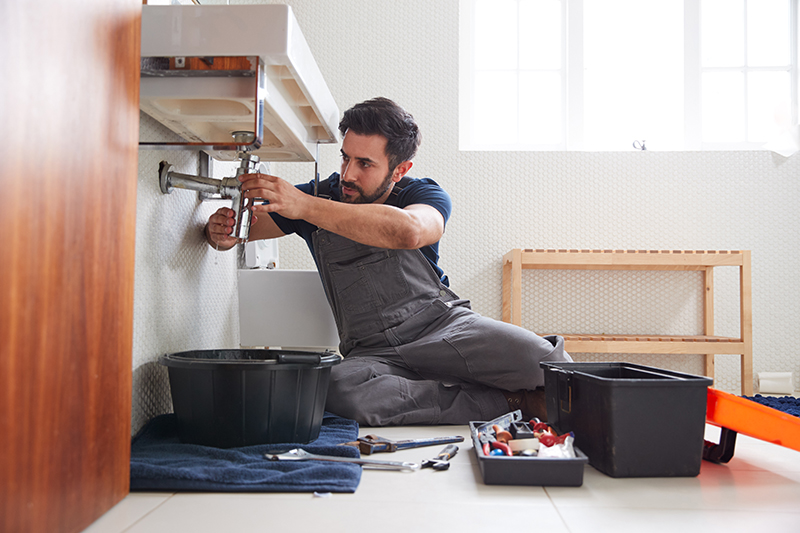 Loodgieter werkt aan verstopte en lekkede gootsteen in badkamer